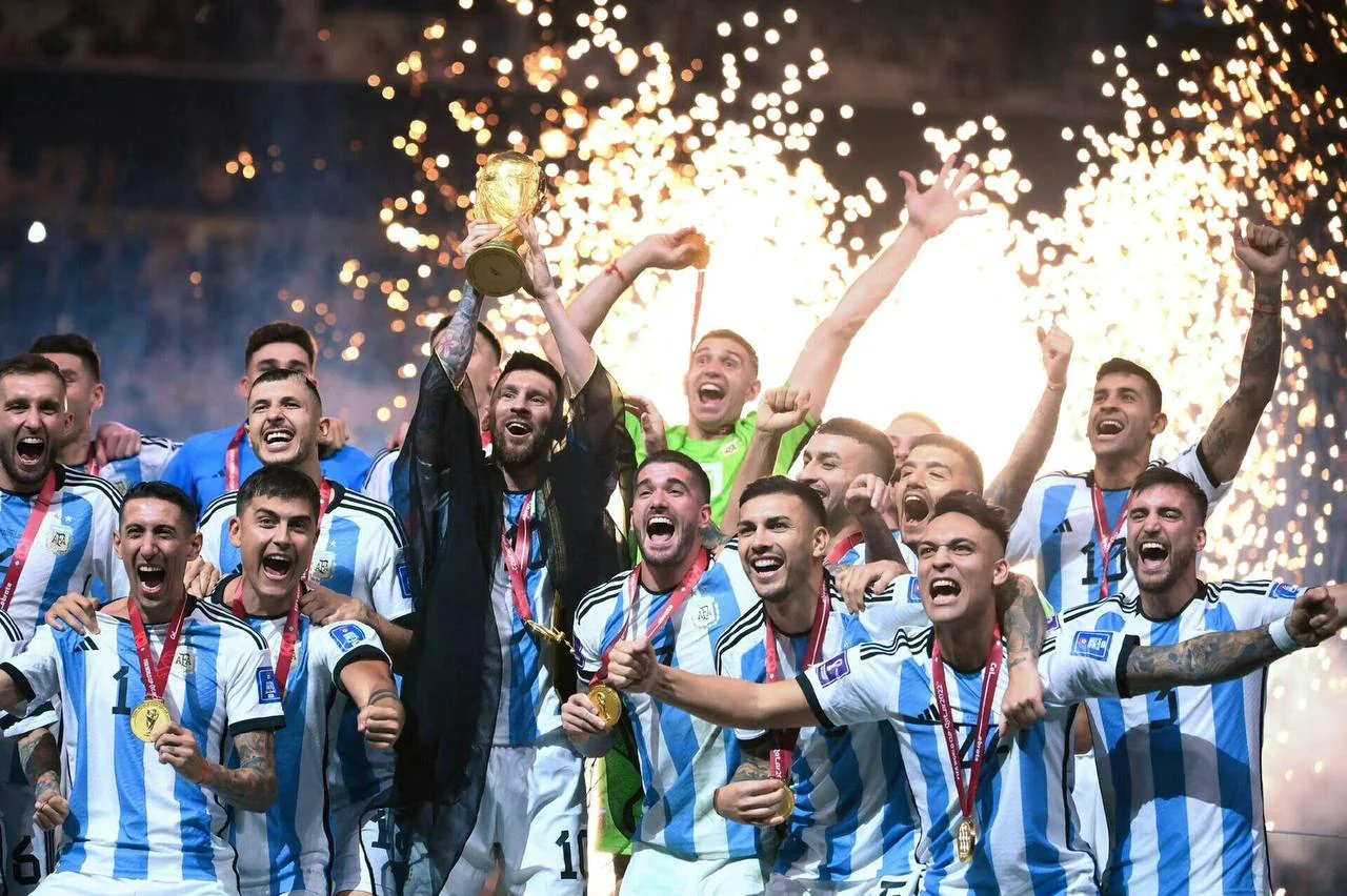 Lionel Messi mengangkat trofi bersama rekan-rekan tim Argentina di tengah perayaan dan kembang api.
